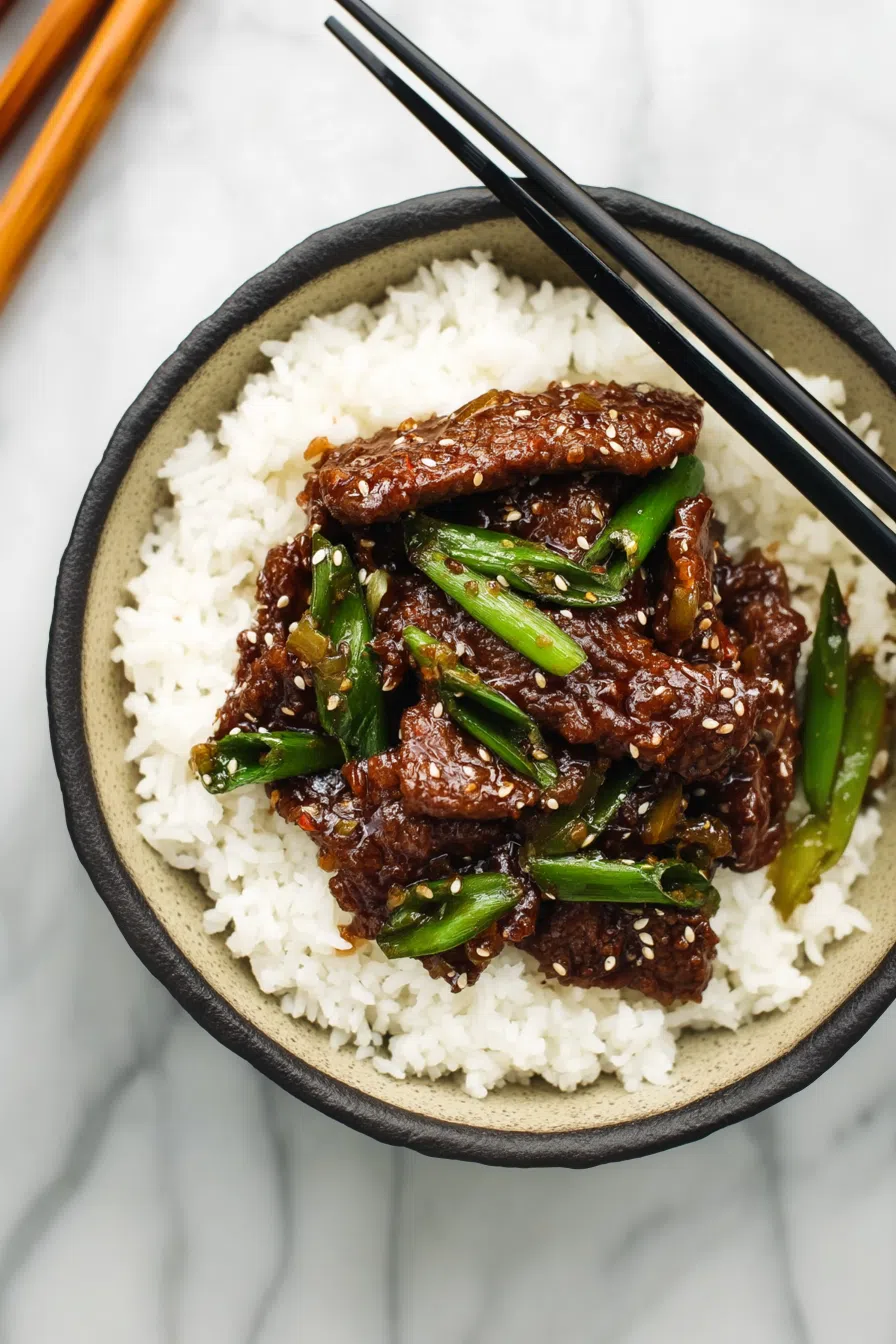 Hearty portion of sauced protein served with rice in a shallow bowl.