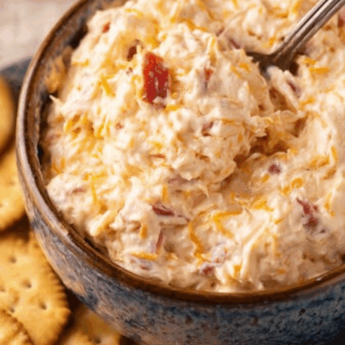 Close-up of a smooth cheese mixture in a glass dish on a wooden table.
