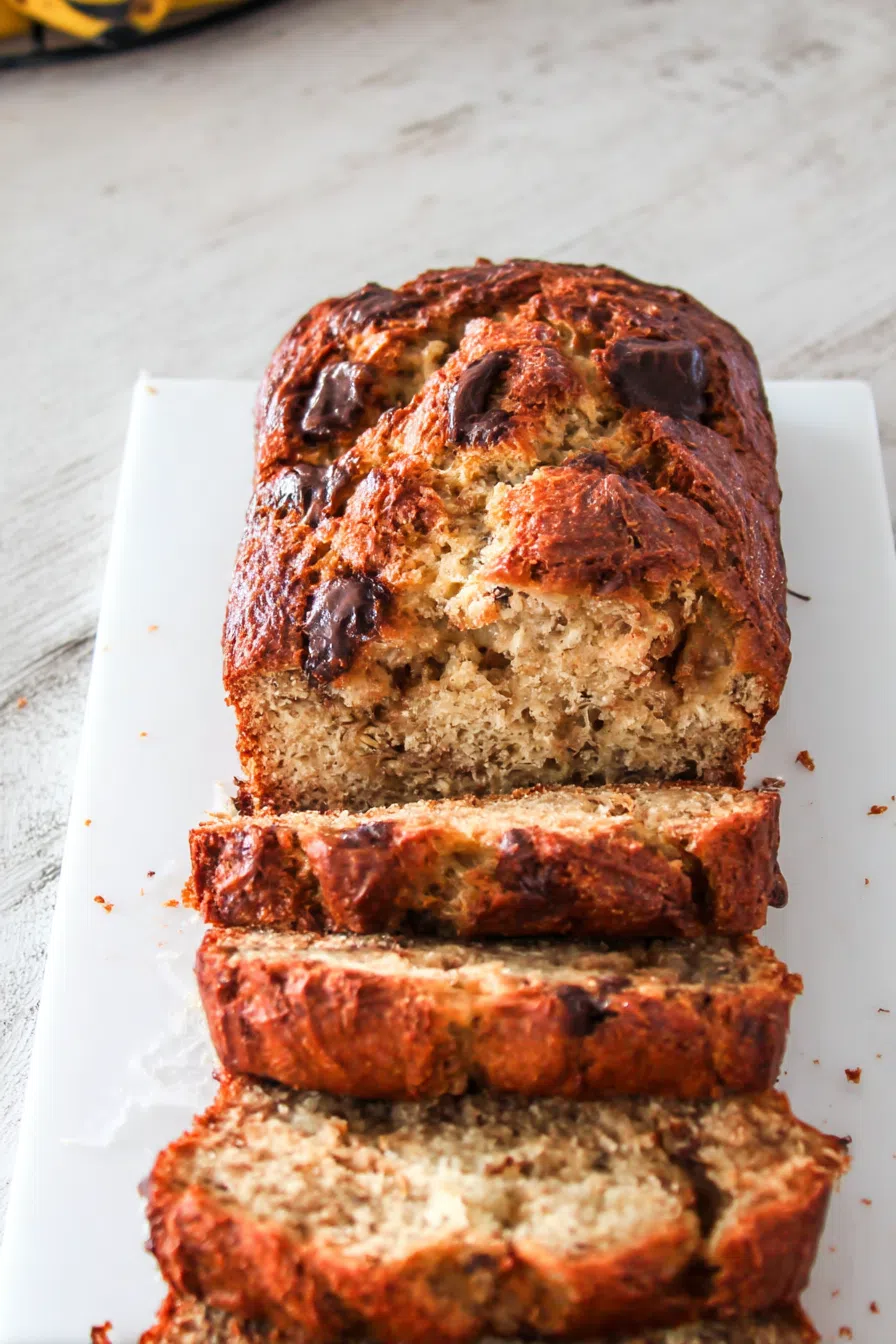 Freshly sliced loaf on a marble board with crumbs scattered around.