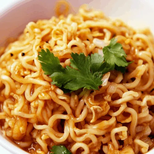 Close-up of a quick noodle dish with red pepper flakes and green onions.