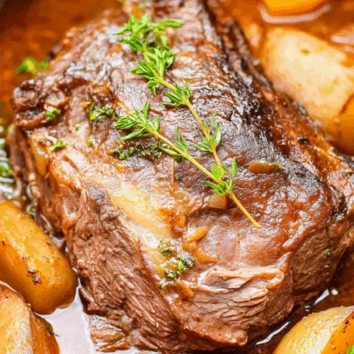 Close-up of juicy beef in a savory sauce, surrounded by cooked onions and potatoes.