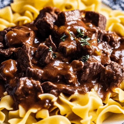 Close-up of saucy meat and egg noodles garnished with fresh parsley.