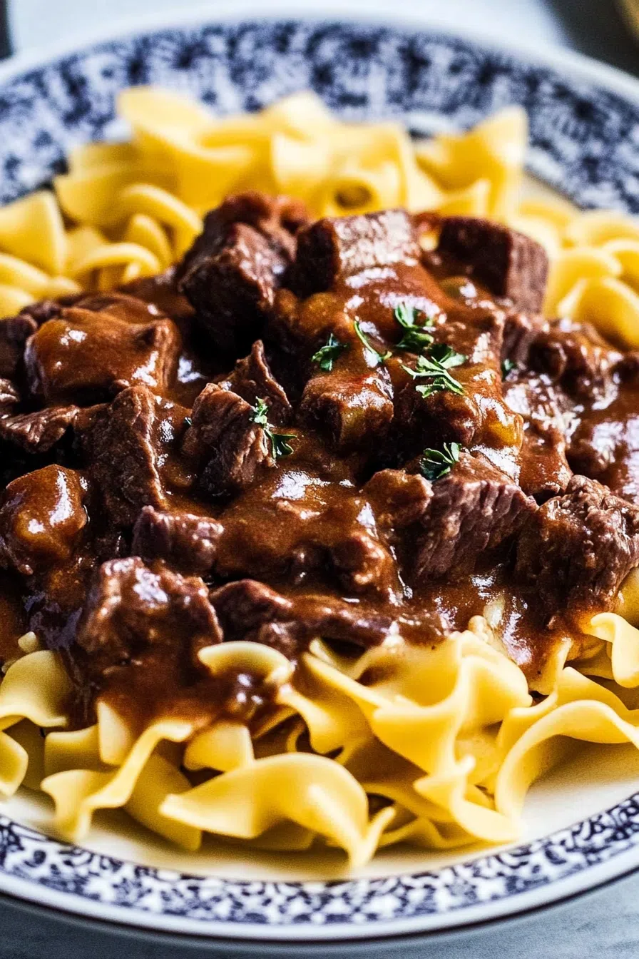 Close-up of saucy meat and egg noodles garnished with fresh parsley.