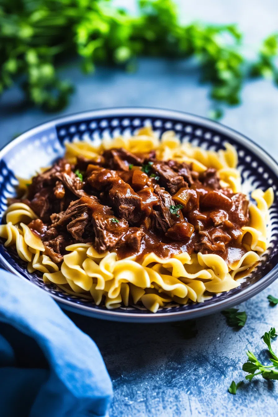 Beef tips with egg noodles served in a shallow bowl, ready to eat.
