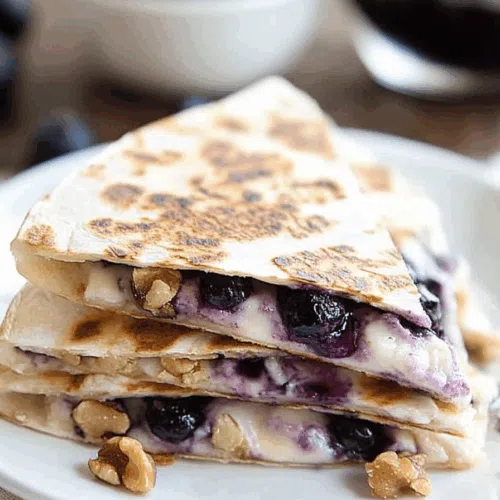 Breakfast quesadilla sliced and stacked with melted filling and fresh fruit on the side.