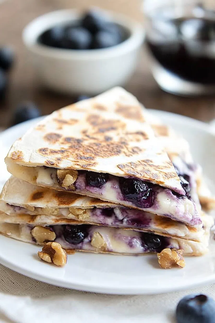 Breakfast quesadilla sliced and stacked with melted filling and fresh fruit on the side.