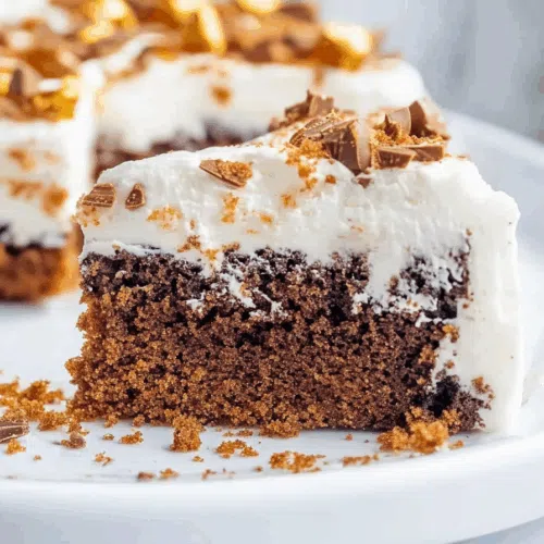 Rich, frosted cake slice served on a dessert plate with visible crunchy toppings.