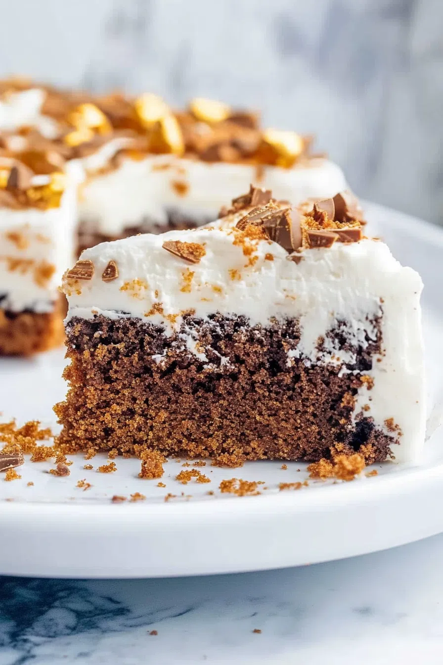 Rich, frosted cake slice served on a dessert plate with visible crunchy toppings.