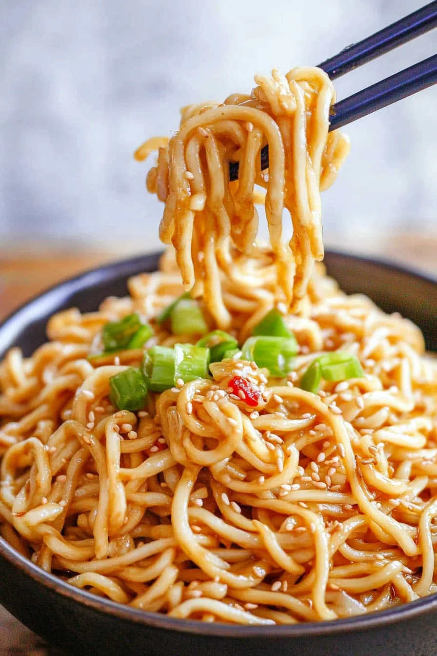 Chopsticks lifting a bite from a colorful, Asian-inspired pasta salad