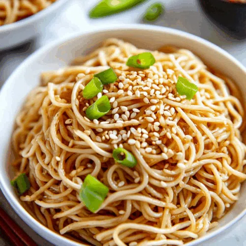 Chilled noodle dish served in a bowl with sliced cucumbers and a sprinkle of sesame seeds