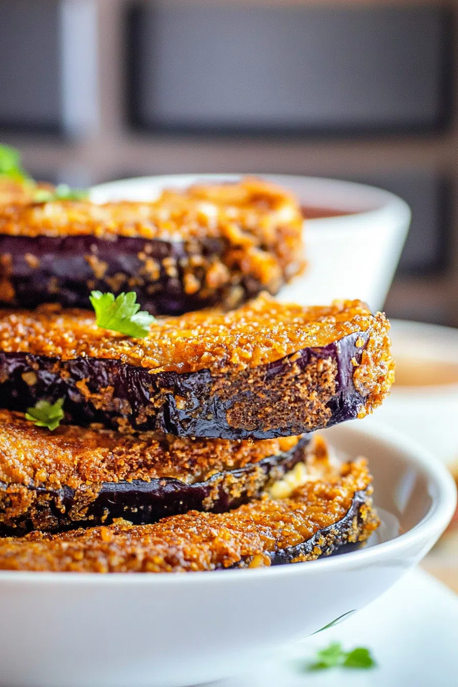 Fried eggplant stacked on a dish, garnished with fresh parsley.