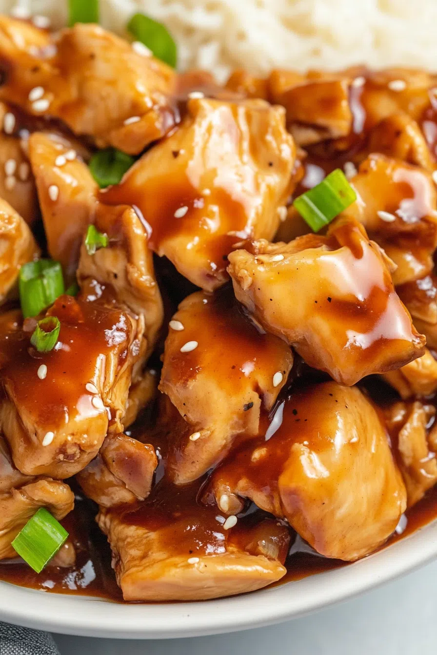Close-up of glazed chicken pieces coated in a thick, glossy sauce.