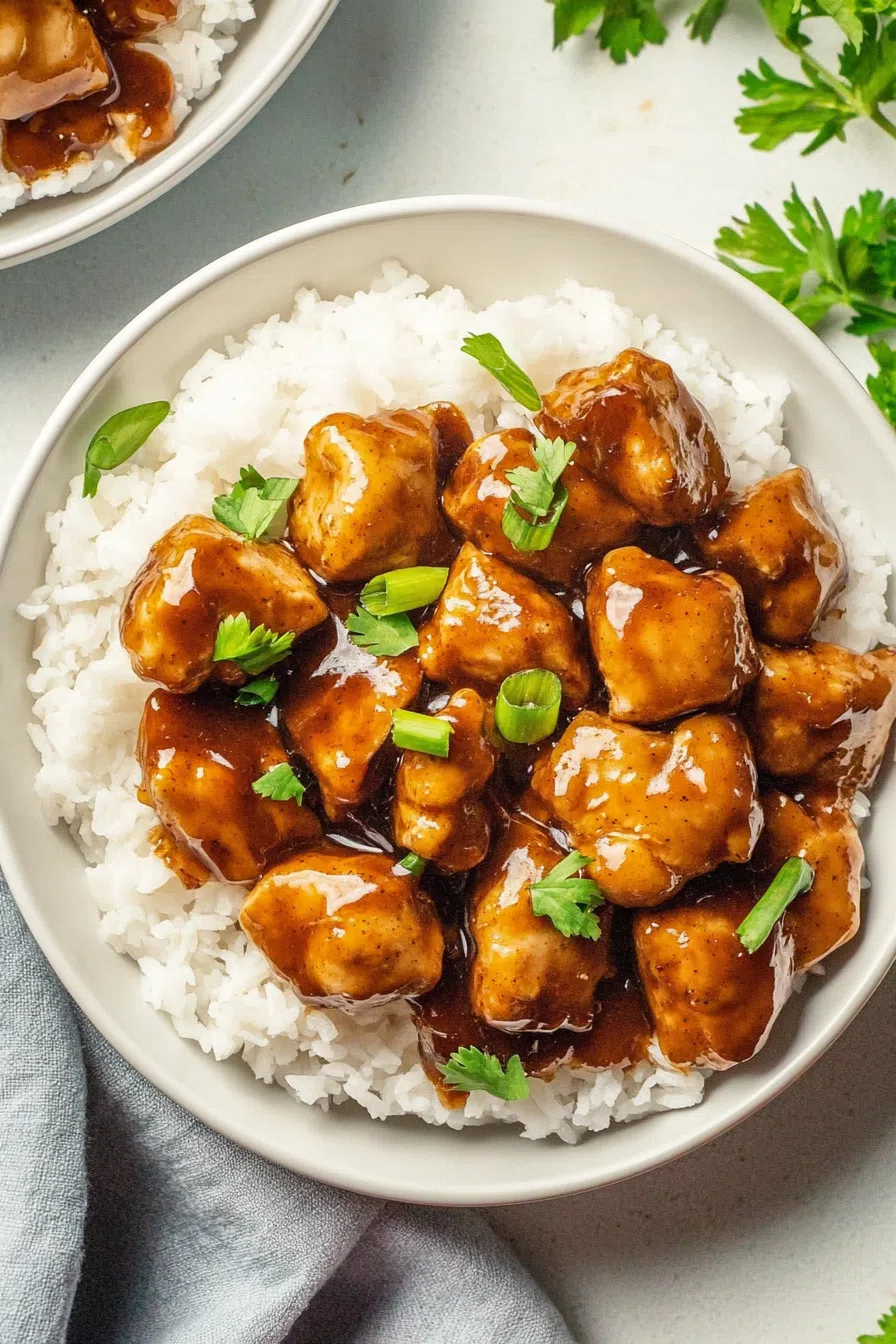 Bite-sized chunks of meat in a savory glaze, garnished with chopped scallions.