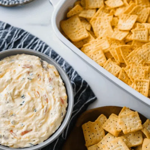 Cheese spread glistening under warm light, ready to be scooped with toast rounds.
