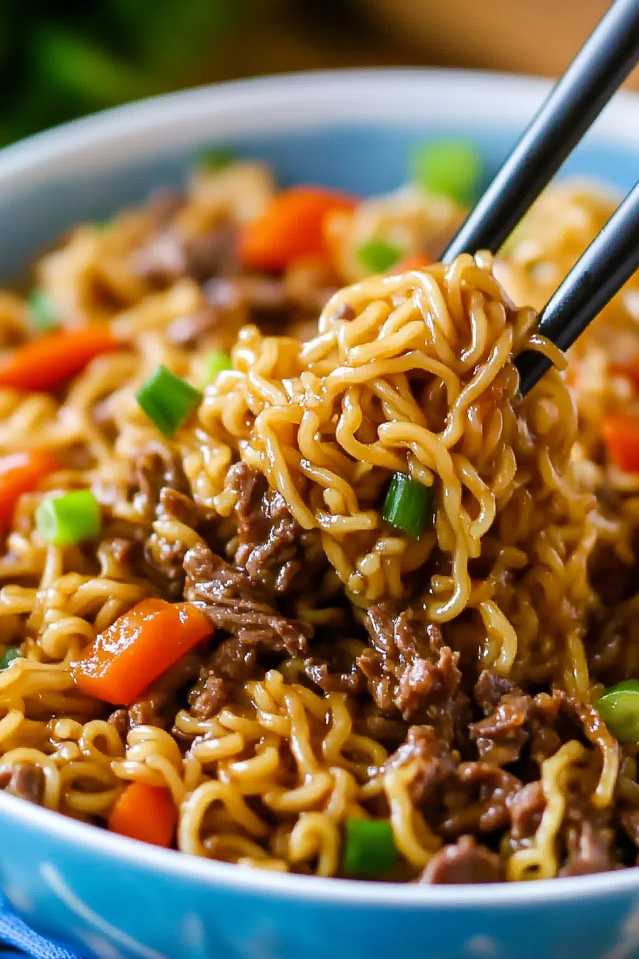 Close-up of chopsticks lifting noodles over a dark ceramic bowl.