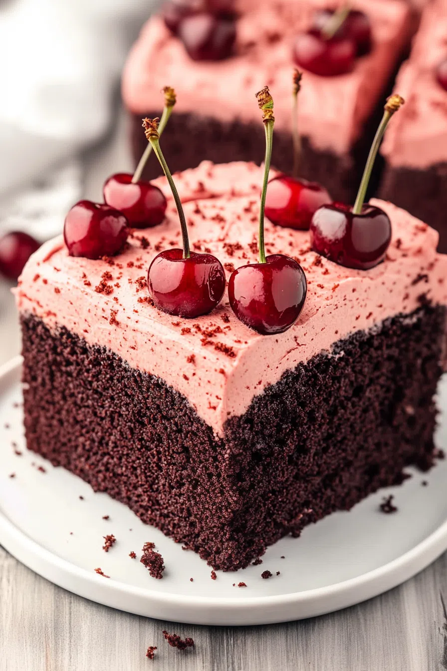 Dark cake with pinkish-red icing displayed on a rustic wooden table.