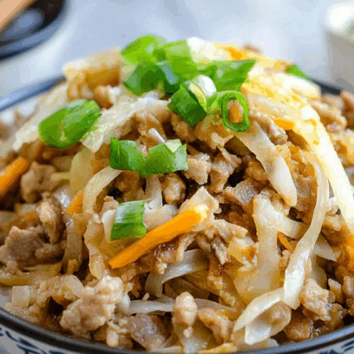 Colorful mixture of cabbage, carrots, and protein garnished with sliced green onions.