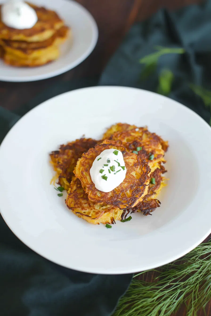 Crispy rounds stacked on a plate with fresh herbs on top.