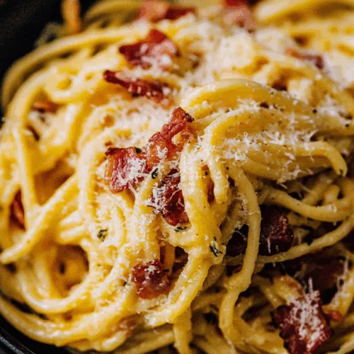 Close-up of a rich, egg-based sauce coating noodles, garnished with herbs