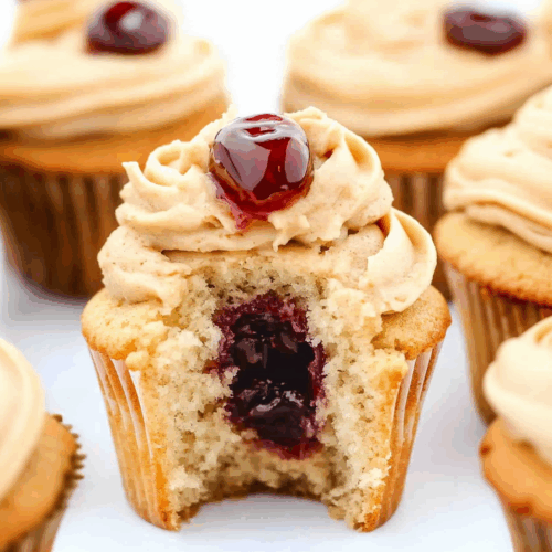 Cupcakes topped with a swirl of creamy frosting and a dollop of fruit filling.