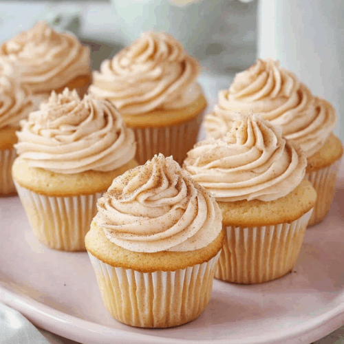 A tray of freshly baked cupcakes cooling on a kitchen counter.