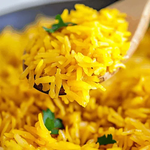 Steaming bowl of vibrant, golden rice topped with fresh herbs.