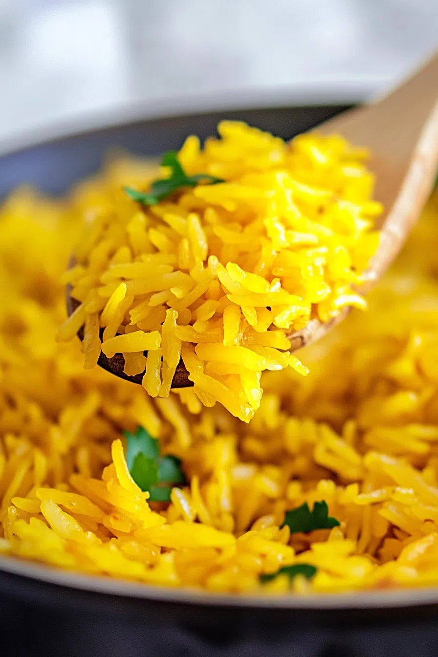 Steaming bowl of vibrant, golden rice topped with fresh herbs.