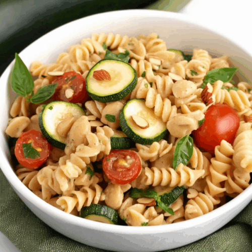 Colorful bowl of pasta with sliced vegetables and slivered nuts