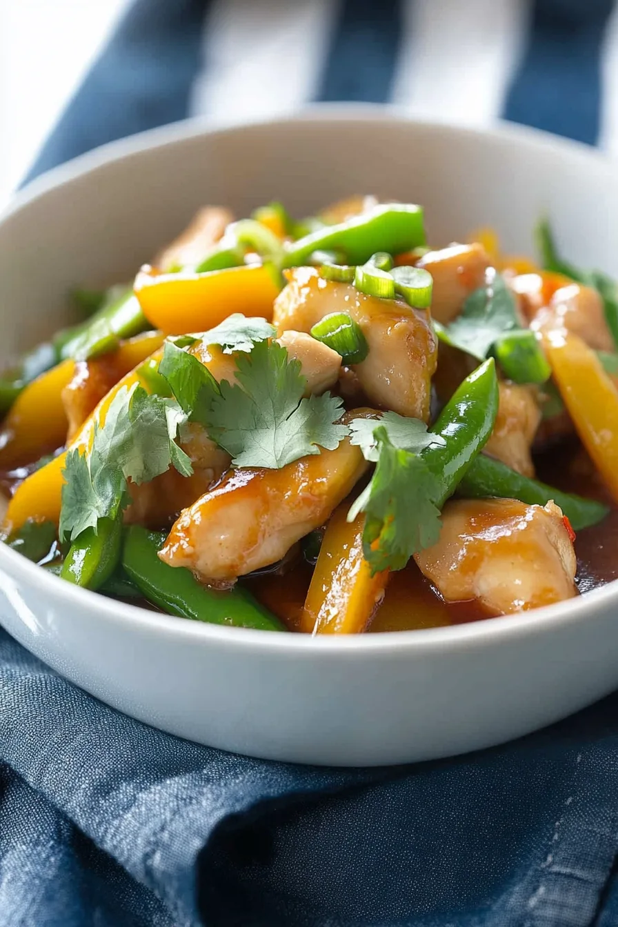 Overhead shot of saucy chicken garnished with sesame seeds and green onions