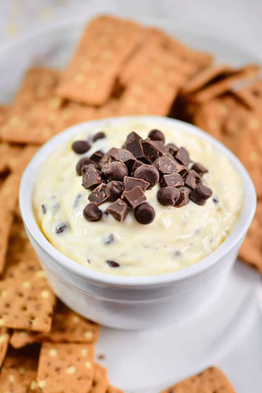 Bowl of creamy dessert dip topped with chocolate chunks.