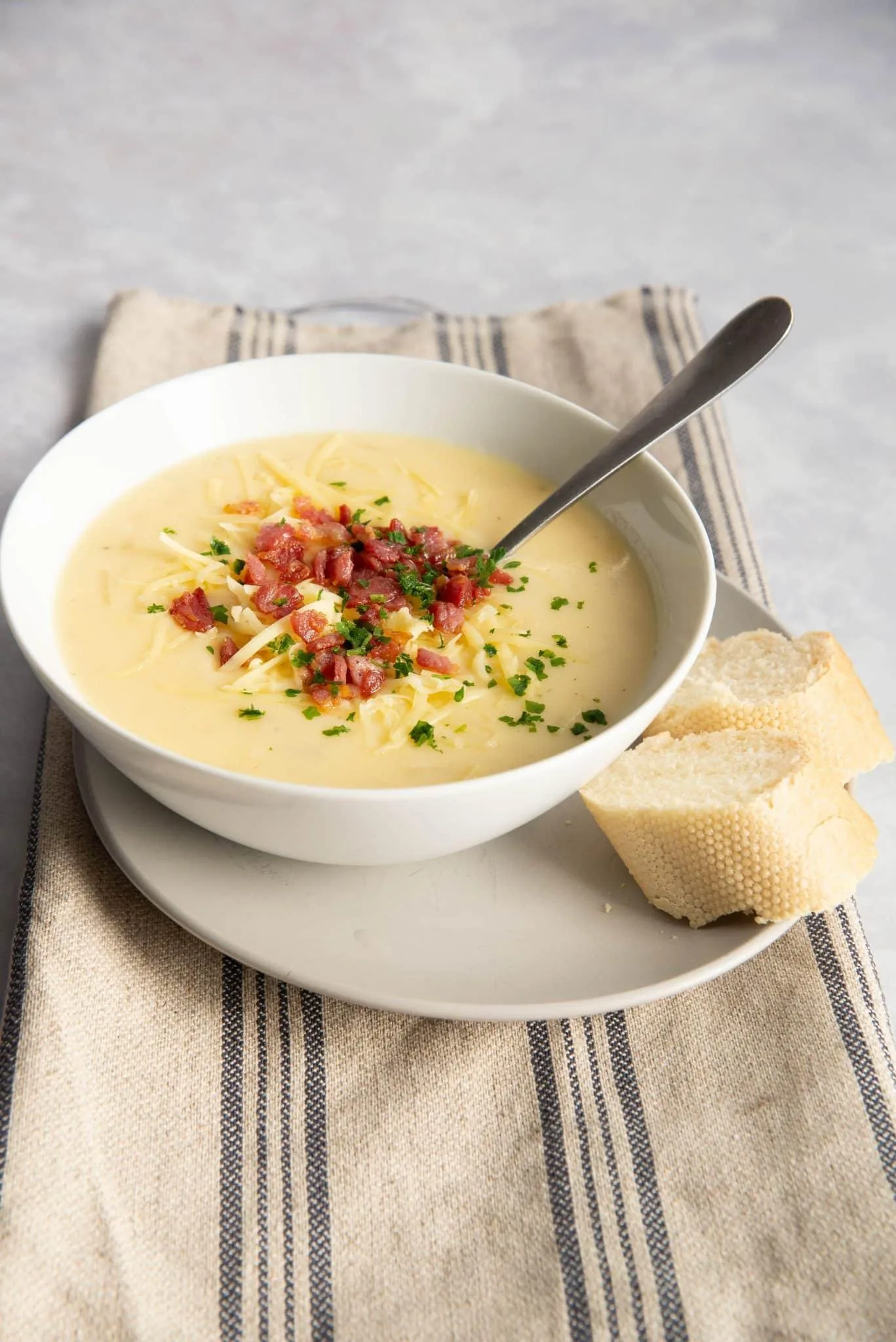 Golden-brown onion soup served in a white bowl with gooey cheese on top.