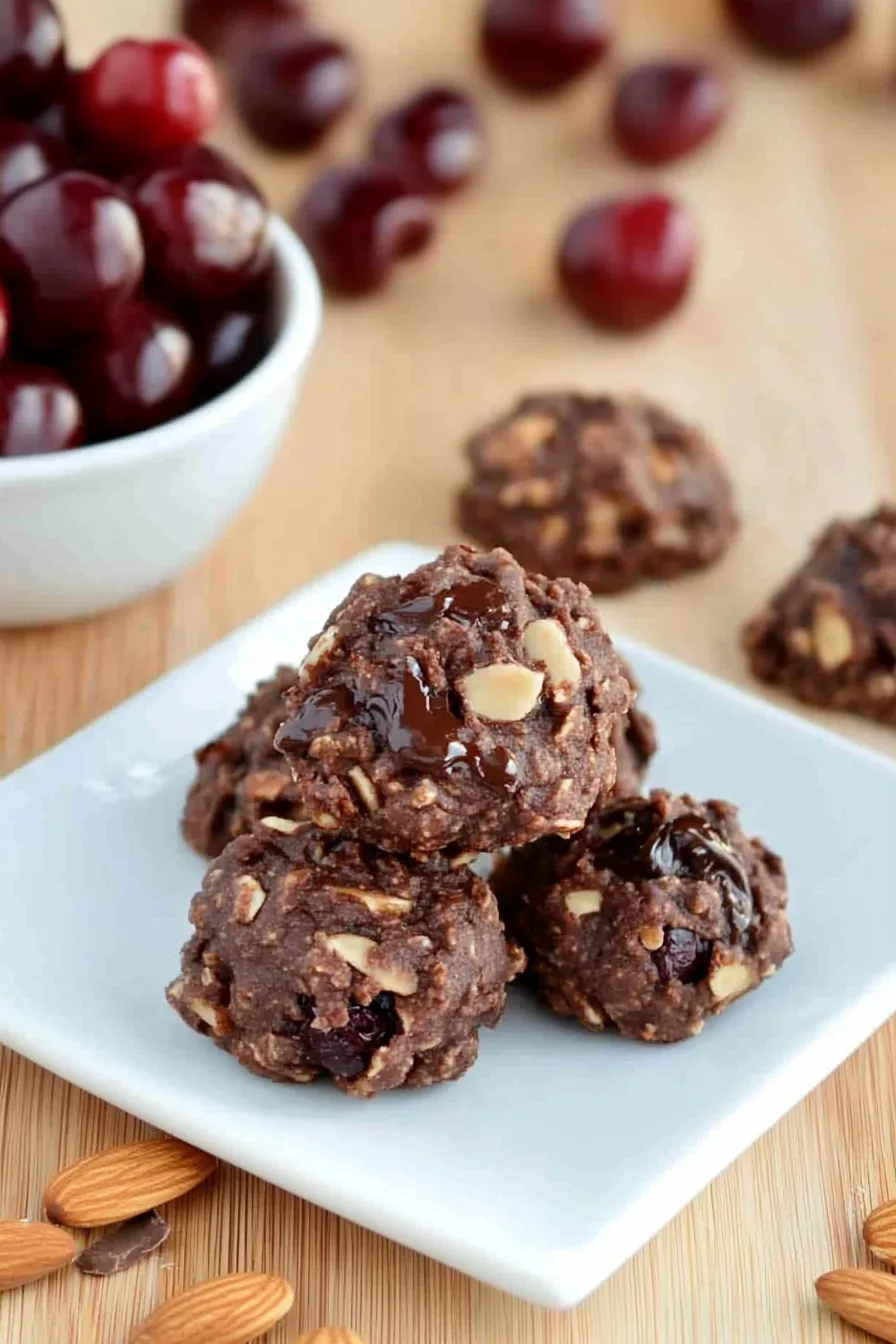 Rich, craggy cookies laid out on parchment paper with a few cherries nearby