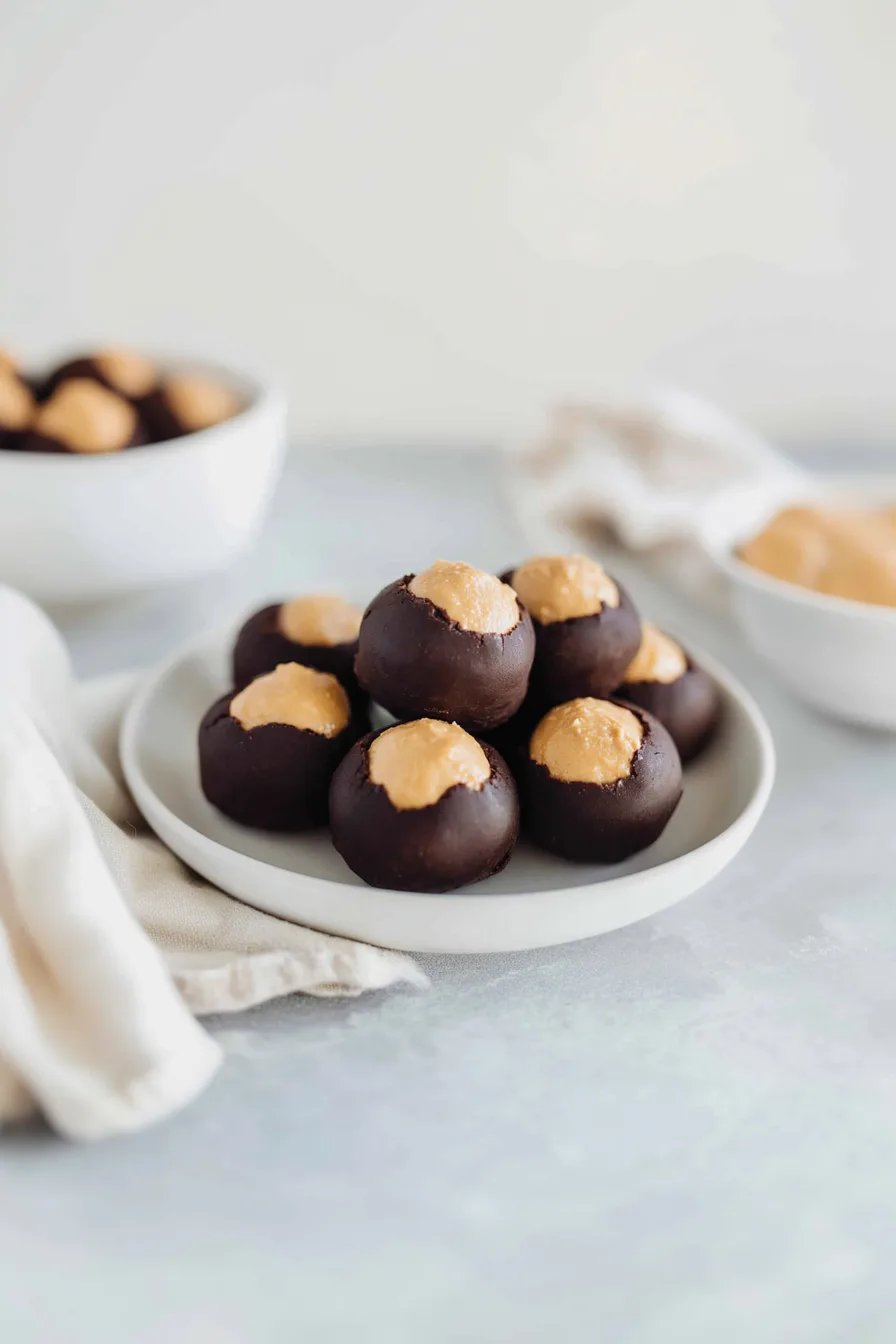 Round chocolate-coated treats arranged neatly on a white plate.