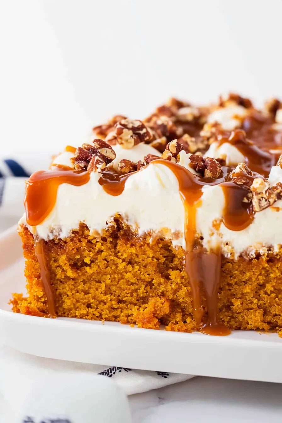 Close-up of Pumpkin Poke Cake with whipped topping and caramel drizzle.