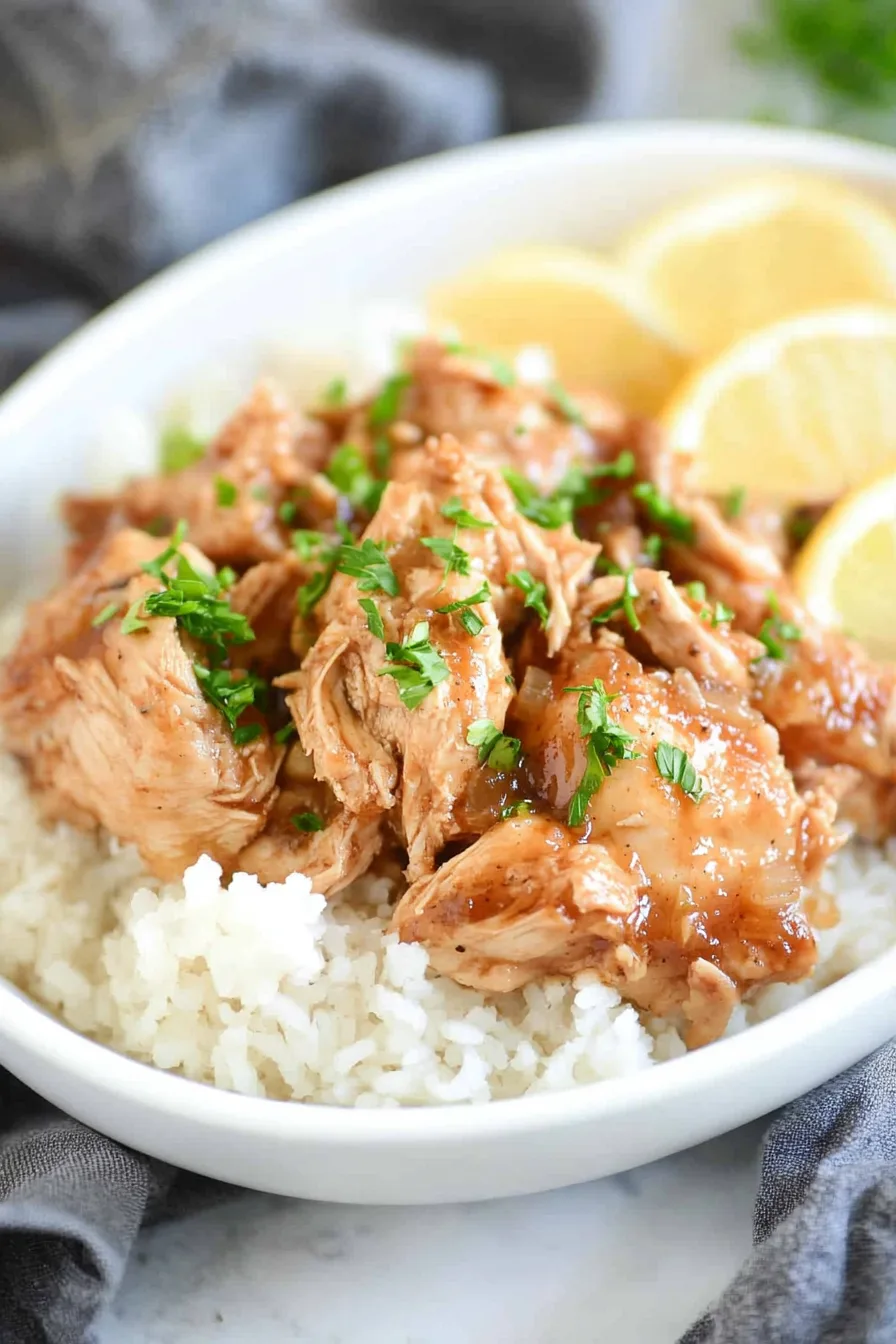Close-up of tender chicken coated in a glossy sweet and tangy sauce.