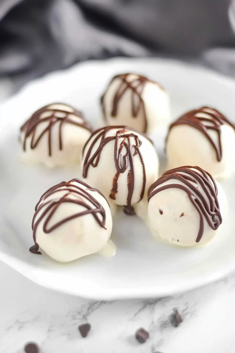 Close-up of creamy cheesecake balls coated in chocolate and drizzled on top.