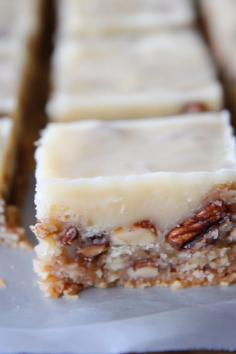 Close-up of frosted pecan bars with a creamy glaze on top.