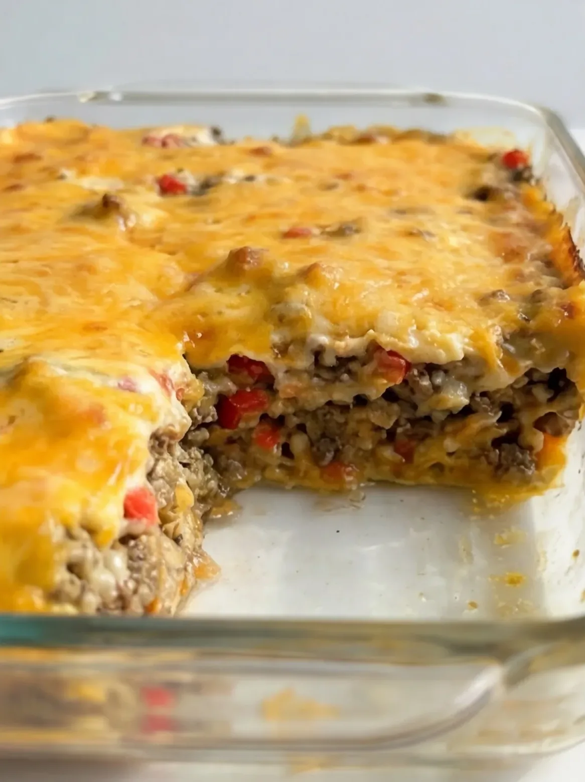 Close-up of casserole layers with seasoned ground beef, diced peppers, and melted cheese