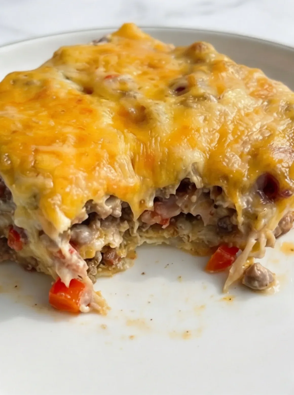 Close-up of cheesy casserole bite showing soft interior and seasoned beef