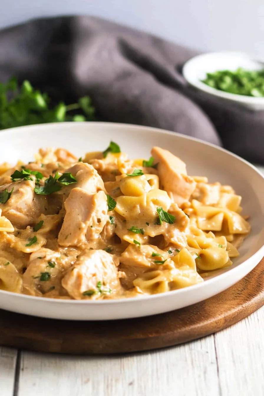 Close-up of spaghetti coated in a rich sauce with chicken chunks.