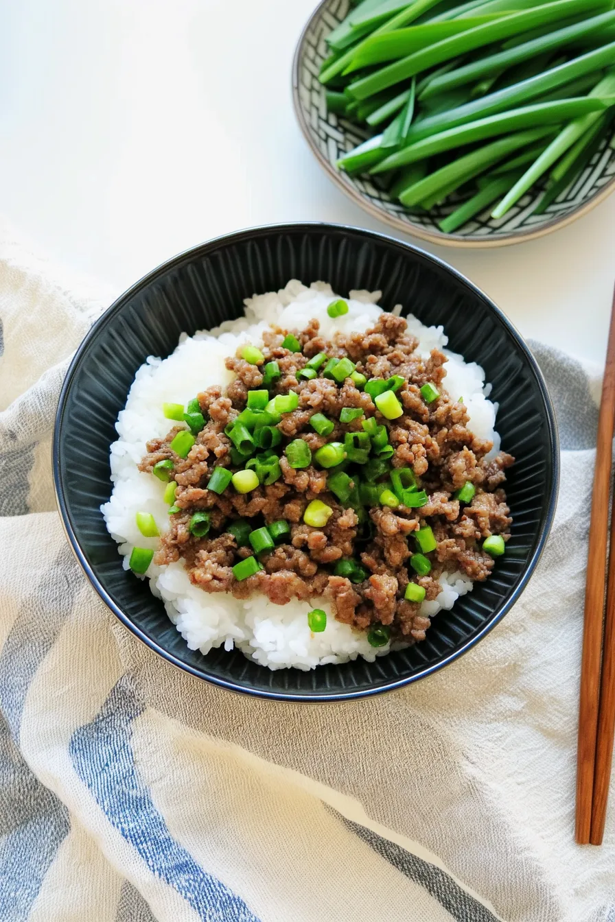 Overhead shot of donburi garnished with green onions and a drizzle of sauce
