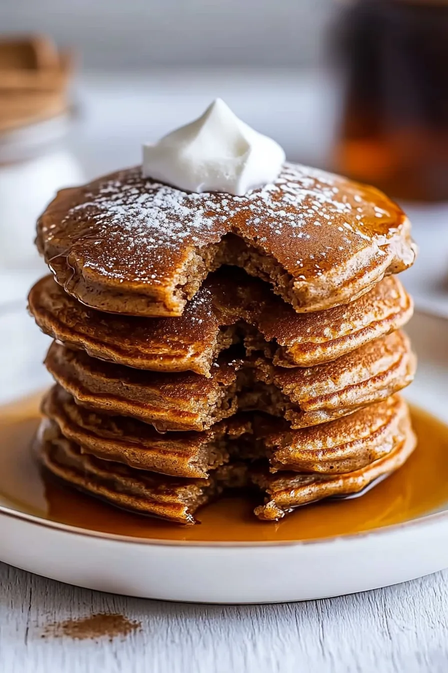 Stack of fluffy pancakes drizzled with syrup and sprinkled with powdered sugar