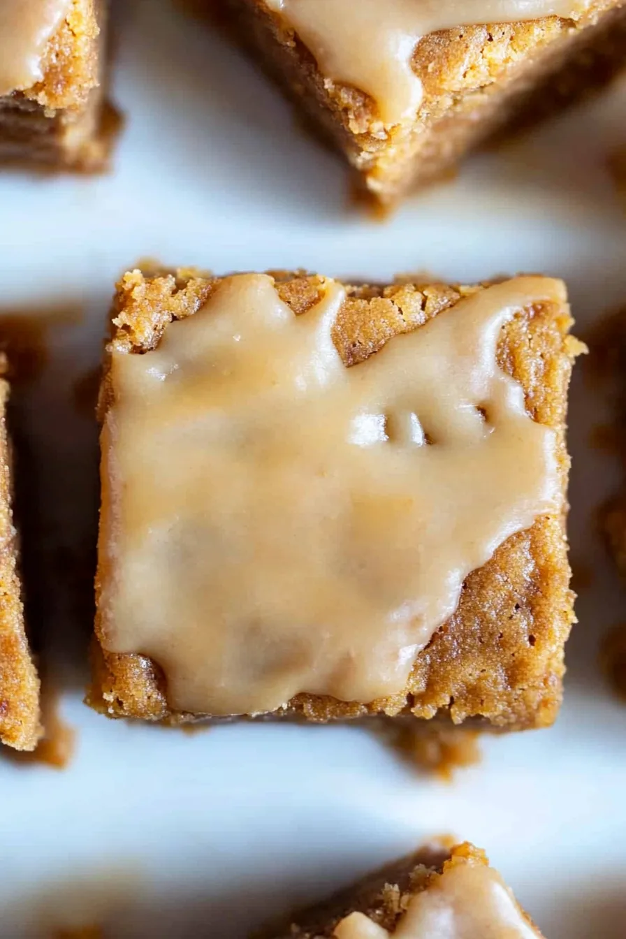 Close-up of spiced apple blondies drizzled with warm maple icing.