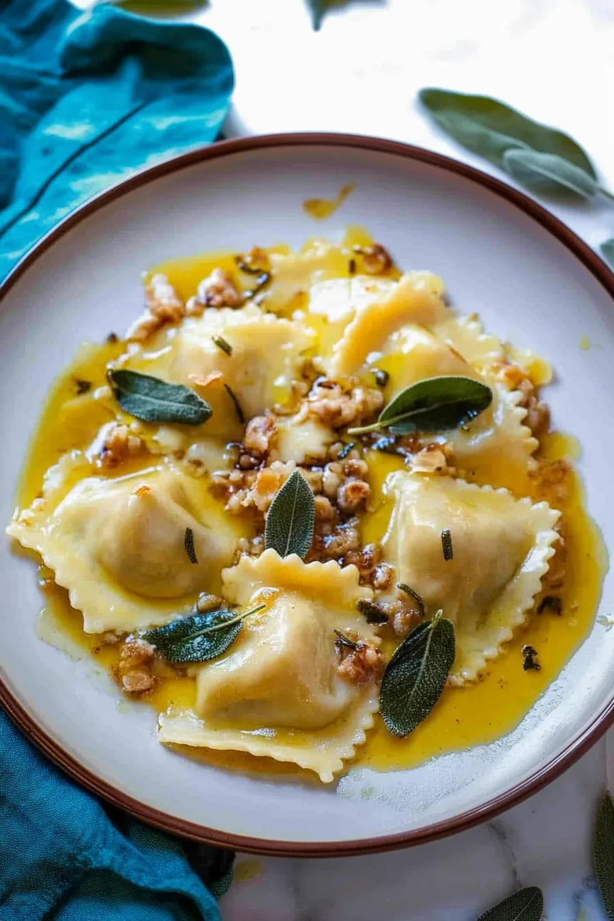 Plate of ravioli in a golden butter sauce with fresh sage leaves