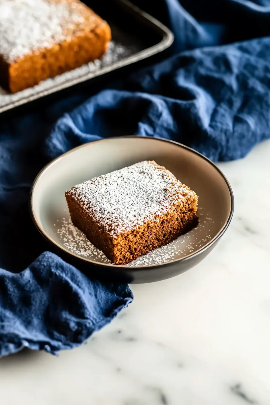 Single piece of tender spice-flavored cake on a plate with sugar dusting.