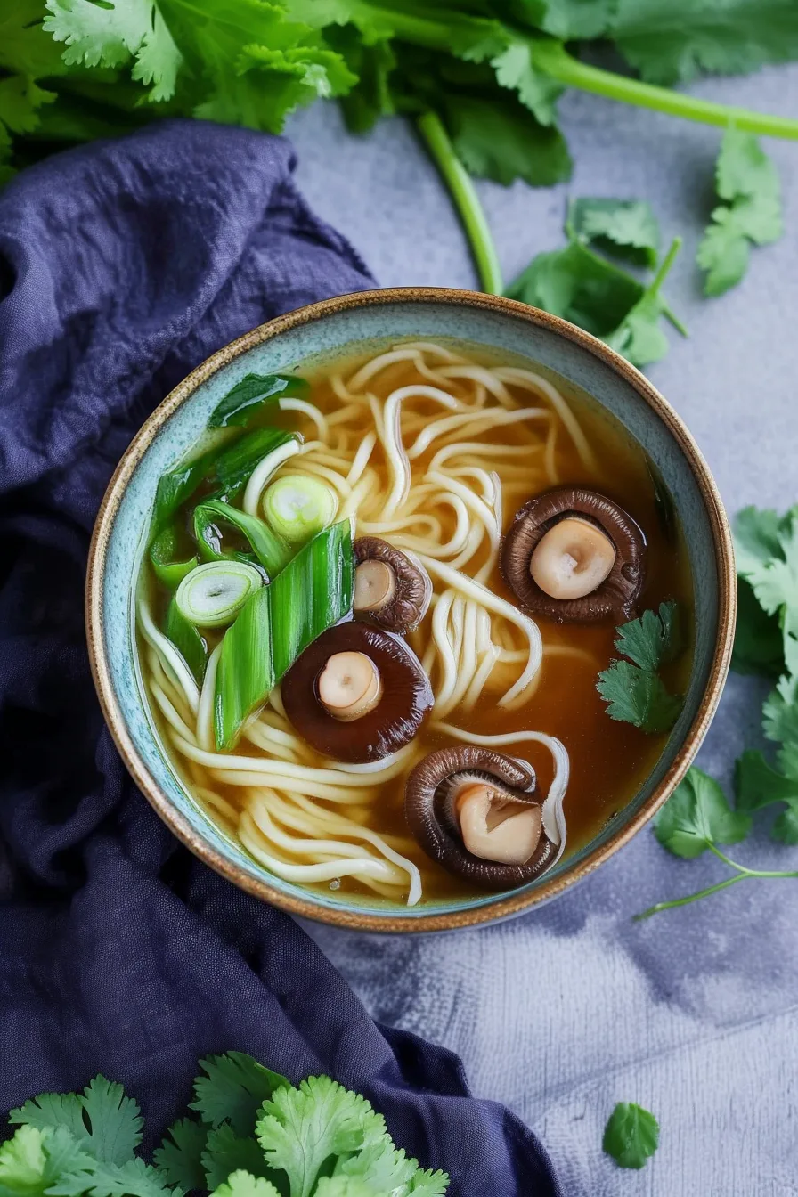 Hearty soup featuring noodles, shredded chicken, and earthy mushrooms served hot.