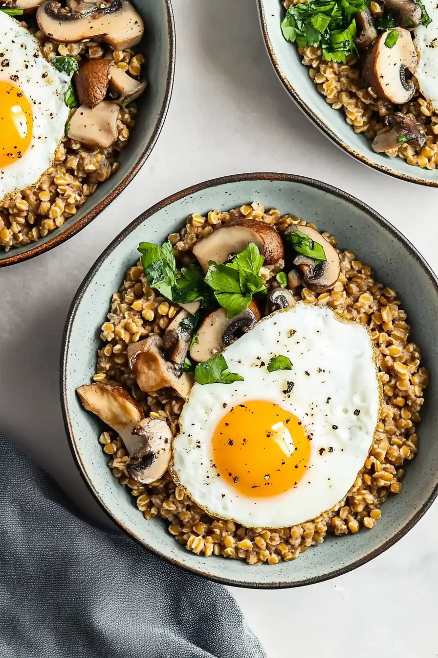 Creamy farro served in a bowl with golden mushrooms and a perfectly cooked egg on top.