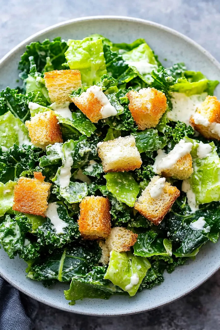 Close-up of crunchy lettuce and kale leaves tossed in Caesar-style dressing.