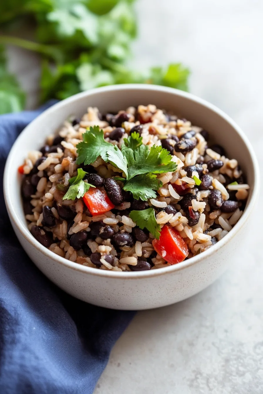 Bowl filled with fluffy rice and tender black beans, topped with herbs.