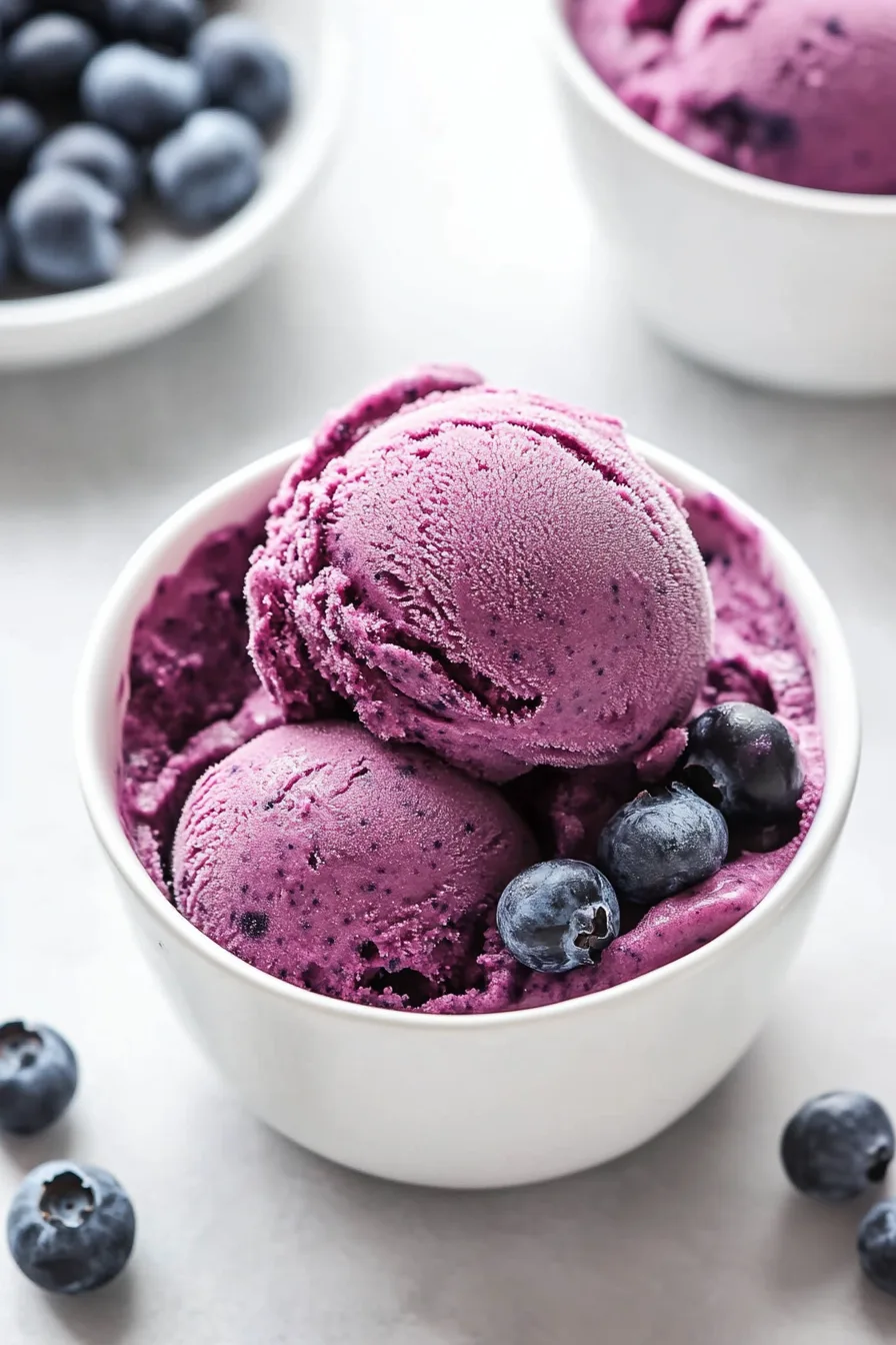 Finished blueberry yogurt dessert garnished with fresh berries on a light surface.